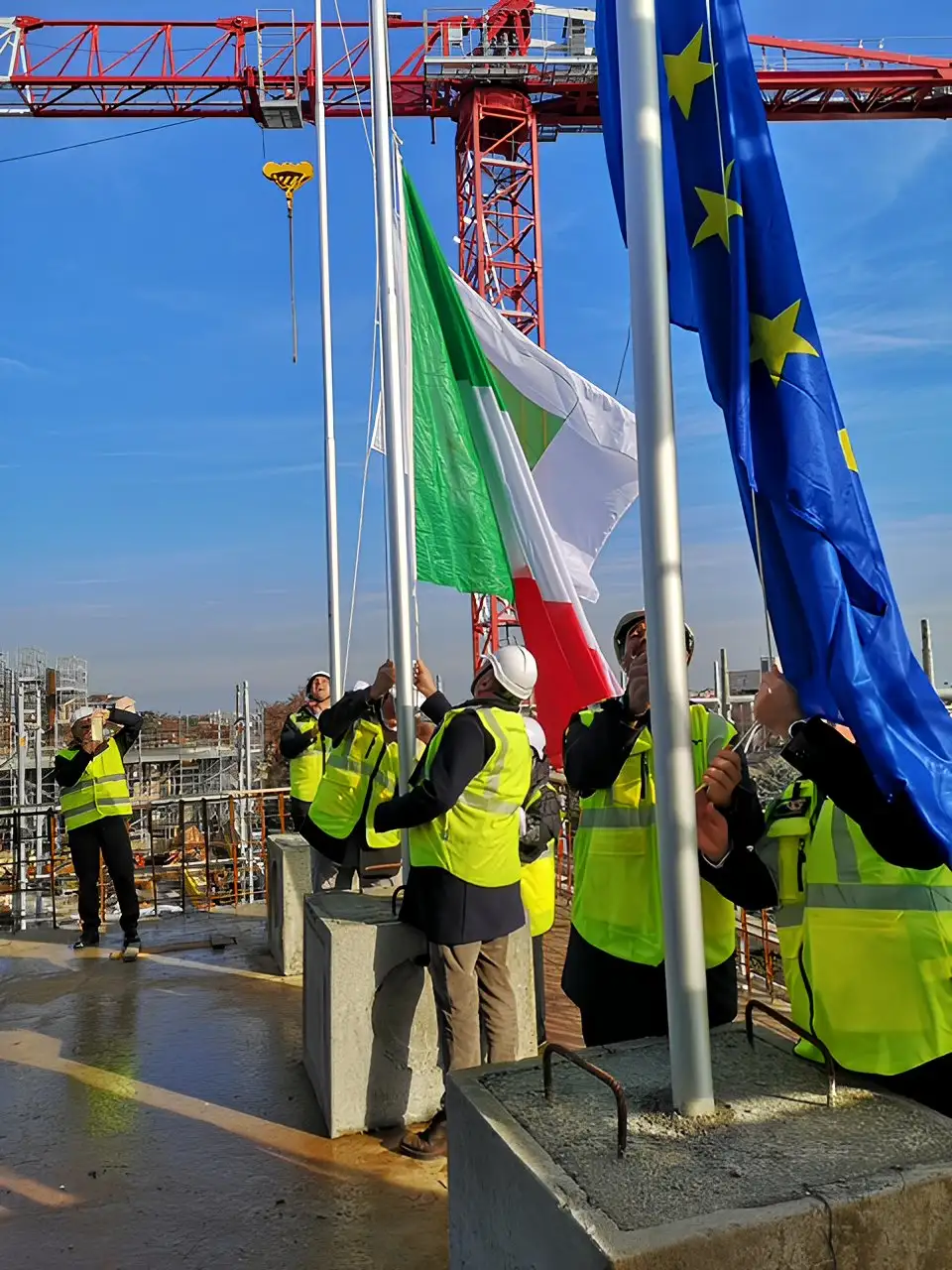 Maestranze mentre issano le bandiere sul tetto del MIRE di Reggio Emilia